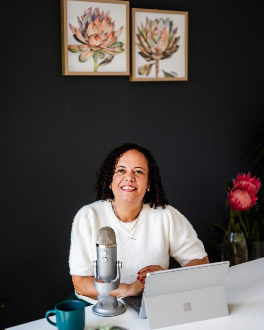 Alicia Noble smiling at her podcast microphone