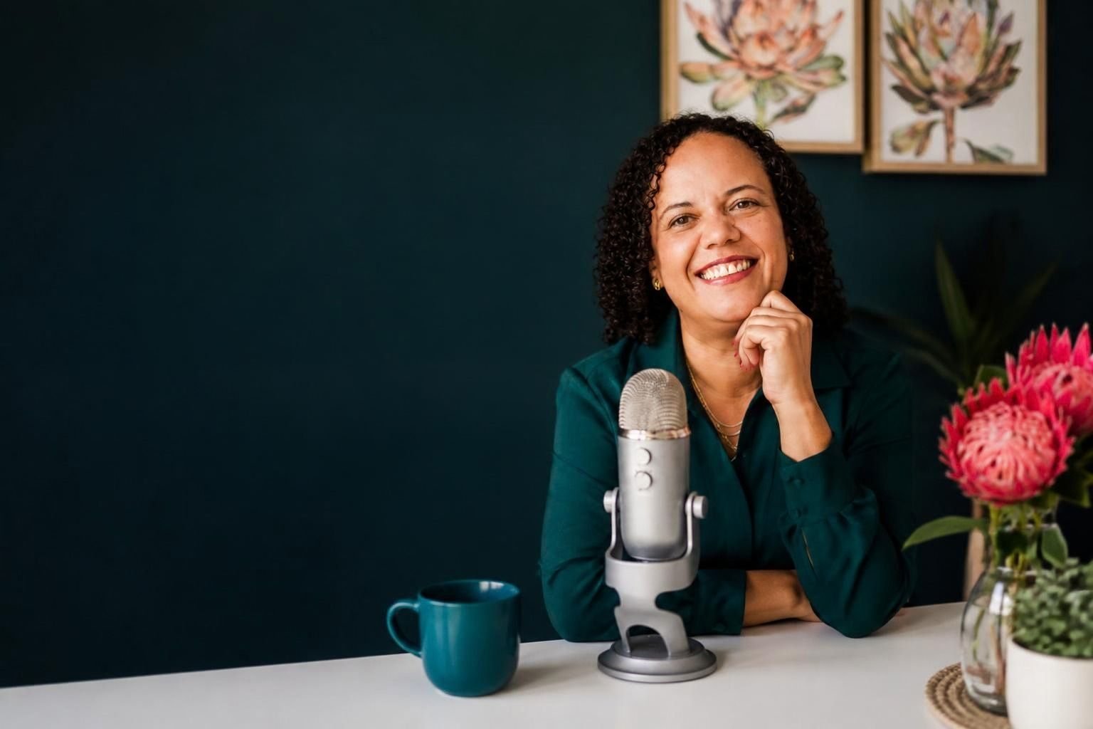 Alicia Noble at her desk with a podcast microphone, smiling